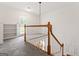Bright hallway with a wooden railing, white trim, and a door leading to a balcony at 107 Edgewater Way, Peachtree City, GA 30269
