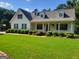 This house features a front porch, a black roof, white siding, and green shutters surrounded by a green lawn at 424 Ivey Edwards Ln, Mcdonough, GA 30253