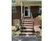 Brick steps lead to a covered porch and front door, framed by iron railings and greenery at 5277 Scofield Rd, South Fulton, GA 30349