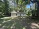 Exterior view of an outbuilding surrounded by lush greenery and mature trees at 5277 Scofield Rd, South Fulton, GA 30349