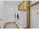 Well-equipped laundry room with wooden cabinets, white washer and dryer, and wood flooring at 100 Walnut Ct, Stockbridge, GA 30281