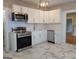 Modern kitchen with stainless steel appliances, white cabinets, and stylish gray and white flooring at 1 Hemlock, Porterdale, GA 30014