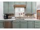 Charming kitchen with unique green cabinets, brick backsplash, and stainless-steel appliances at 396 Ebenezer Rd, Fayetteville, GA 30215
