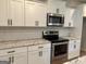 Modern kitchen featuring white cabinets, stainless steel appliances, and beautiful backsplash for a stylish cooking space at 248 Webster Lake Dr, Temple, GA 30179