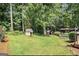Large backyard with green grass, mature trees, a dog house, and a distant shed, perfect for outdoor enjoyment at 4352 Treeline Way, Douglasville, GA 30135