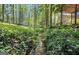 Picturesque backyard with lush greenery, a serene stream, and a charming footbridge leading to a covered structure at 4352 Treeline Way, Douglasville, GA 30135