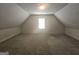 Spacious, carpeted attic with a single window, offering potential for storage or customization at 4680 Duval Point Sw Way, Snellville, GA 30039