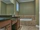 Bathroom featuring double sinks, a large mirror, and a luxurious tiled bathtub for a relaxing spa-like experience at 834 Chalet Hills, Mcdonough, GA 30253