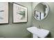 A charming bathroom boasts olive-colored walls, framed art, pedestal sink, and silver round mirror at 10422 Trellis Lane (Lot 38), Hampton, GA 30228