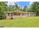 Rear exterior view of the home showcasing a large wooden deck, manicured lawn, and wooded backdrop at 351 Weldon Rd, Palmetto, GA 30268