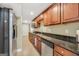Galley kitchen featuring wooden cabinetry, granite countertops, stainless steel appliances, and tiled floors at 106 Big Cotton Trl, Mcdonough, GA 30252
