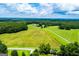 An aerial view features the vast acreage with grass fields and a single track drive to the structures at 1074 Glenloch Rd, Roopville, GA 30170
