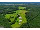 An aerial view shows the vast property, home and barns bordered by lush trees at 1074 Glenloch Rd, Roopville, GA 30170