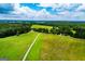 An aerial view shows the vast property with farm land with a long white driveway at 1074 Glenloch Rd, Roopville, GA 30170
