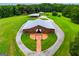 Aerial view of brown barn with a circular driveway and landscaped entrance, surrounded by green lawns at 1074 Glenloch Rd, Roopville, GA 30170