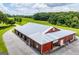 Expansive red and brown barn with a silver roof and multiple access points, set against a green field with trees at 1074 Glenloch Rd, Roopville, GA 30170