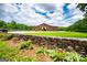 Large barn with stone pillars, lush lawn, and a stone wall at 1074 Glenloch Rd, Roopville, GA 30170
