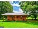 The cabin's covered front porch features two chairs and large decorative metal wheel at 1074 Glenloch Rd, Roopville, GA 30170