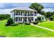 Stately white brick home featuring a covered front porch, manicured lawn, and beautiful landscaping at 1074 Glenloch Rd, Roopville, GA 30170