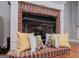 Close-up shot of the brick fireplace hearth, pillows, and decor at 1074 Glenloch Rd, Roopville, GA 30170