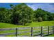 Fenced in pasture on the property is framed by mature shade trees at 1074 Glenloch Rd, Roopville, GA 30170