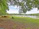 Scenic lake view featuring chairs, kayaks, lush grass, and tree surroundings at 504 Ridgelake Dr, Peachtree City, GA 30269