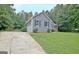 Side view showing a gray house with a well-kept lawn and driveway, with a partial view of the garage at 85 Holly Springs Rd, Sharpsburg, GA 30277