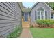 Close-up of front entrance with wooden steps and landscaping; the home features gray siding at 85 Holly Springs Rd, Sharpsburg, GA 30277