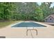 In-ground pool surrounded by concrete with deck area and surrounded by backyard trees at 85 Holly Springs Rd, Sharpsburg, GA 30277