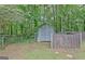 A storage shed with a chain link fence located in a wooded backyard at 85 Holly Springs Rd, Sharpsburg, GA 30277