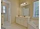 Bright bathroom featuring a white vanity with a large mirror, tub with tiled flooring and window at 155 Westminister Village Blvd, Sharpsburg, GA 30277