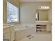 Bright bathroom featuring a soaking tub, vanity with makeup station, tiled flooring and window at 155 Westminister Village Blvd, Sharpsburg, GA 30277