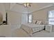 Bright main bedroom featuring a tray ceiling, carpeted floors, and a view of the windows at 155 Westminister Village Blvd, Sharpsburg, GA 30277