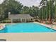 Community pool with surrounding lounge furniture and a clubhouse on a sunny day at 155 Westminister Village Blvd, Sharpsburg, GA 30277