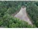 Aerial view showcasing a serene lake surrounded by dense, lush green trees, and nearby houses at 6111 Old Monticello Se St, Covington, GA 30014