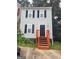 Two-story home featuring gray siding, black shutters, and a black front door with bright orange painted stairs at 2052 Charter Ln, Lithonia, GA 30058