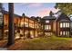 Expansive backyard featuring a covered porch, brick facade, well-manicured lawn, and spiral staircase at 4874 Kettle River Pt, Suwanee, GA 30024