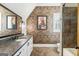 Bathroom showcasing brick wall, dark countertops, and double sink vanity at 4874 Kettle River Pt, Suwanee, GA 30024
