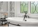 Close up of the soaking tub in the elegant, all-white primary bath with stylish fixtures at 4874 Kettle River Pt, Suwanee, GA 30024