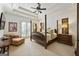 Primary bedroom featuring a tray ceiling, a four poster bed, and private doors to the outside at 4874 Kettle River Pt, Suwanee, GA 30024