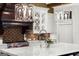Chef's kitchen featuring custom cabinetry, Wolf range, brick accents, and a large marble island at 4874 Kettle River Pt, Suwanee, GA 30024