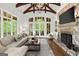 Bright living room featuring a stone fireplace, beamed ceilings, hardwood floors, and French doors at 4874 Kettle River Pt, Suwanee, GA 30024