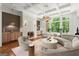 Elegant living room featuring tray ceilings, curved seating, fireplace, and large windows overlooking lush greenery at 4874 Kettle River Pt, Suwanee, GA 30024