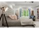 Spacious main bedroom showcasing a luxurious bed, large window with curtains, and a cozy seating area at 4874 Kettle River Pt, Suwanee, GA 30024