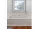 Bright bathroom showcasing a soaking tub beneath a window, set on wood flooring at 320 Cloverwood Drive, Fayetteville, GA 30215