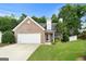 Charming brick home featuring an attached garage, well-manicured lawn, and mature trees at 320 Cloverwood Drive, Fayetteville, GA 30215