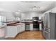 Well-lit kitchen with stainless steel appliances, white cabinets, laminate countertops, and wood look floors at 320 Cloverwood Drive, Fayetteville, GA 30215