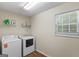 A compact laundry room, featuring a washer, dryer, storage shelf and a bright window at 315 Antioch Road, Mcdonough, GA 30252