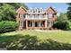 Elegant two-story brick home with a decorative balcony, black shutters, and meticulously maintained landscaping at 100 Castlebrook Chase, Tyrone, GA 30290
