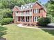 Spacious two-story red brick home with a balcony, complemented by a well-manicured front lawn at 100 Castlebrook Chase, Tyrone, GA 30290